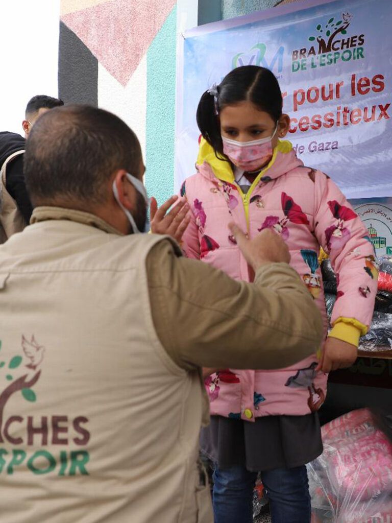 Bénévole remettant un cadeau à une fillette lors d'une distribution à Gaza